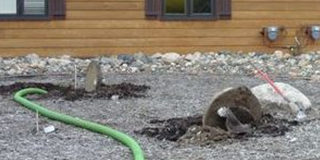 Open septic tank with green drainage hose