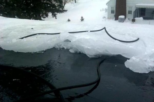 Icy lake near a home with black hosing
