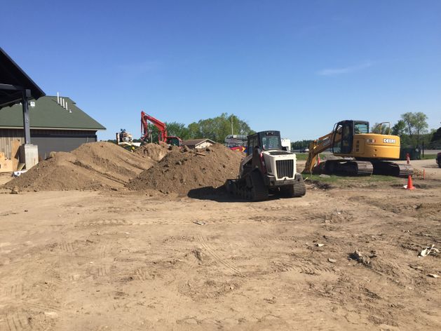 Several construction vehicles surrounding piles of sand and dirt