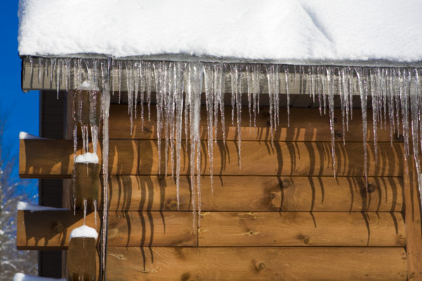 Icicles hanging from a snowy cabin roof